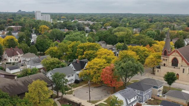 Aerial drone view of Green Bay Wisconsin autumn neighborhood with church in the foreground and Lambeau Field in the distance, reveals grocery store