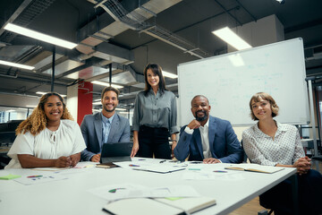 Group of happy multiracial adults looking at camera during business meeting in office