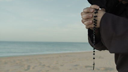 Religious Hands Of A Monk Praying Rosary On The Beach - obrazy, fototapety, plakaty