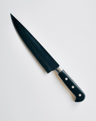 On a white background, a large, sombre kitchen knife.
