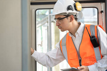 Portrait Asia male engineer in protective workwear is checking a electrical control cabinet or circuit electric control button with tablet computer at rooftop building	