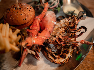 A plate of food with a burger, fries, and crab legs