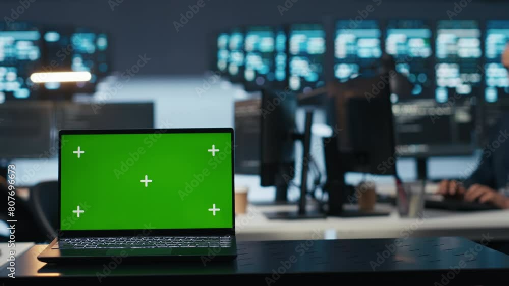 Poster focus on isolated screen laptop in data center with man in blurry background coding, managing server