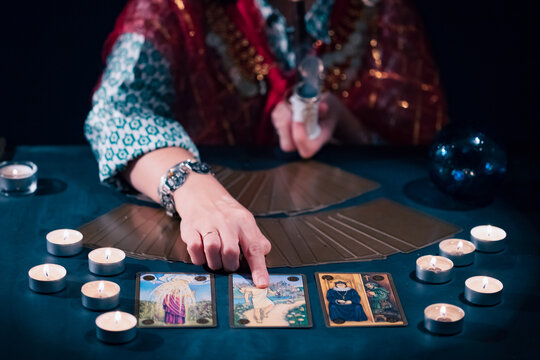 Tarot reader with tarot cards.Tarot cards face down on table near burning candles and crystal ball.