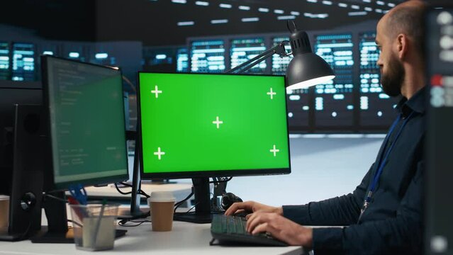 IT employee programming on green screen PC in data center housing supercomputers storing datasets. Admin writing code on mockup computer monitor to mend data center racks