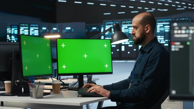 IT supervisor working on isolated screen computers in data center, ensuring optimal performance. Person monitoring energy consumption across servers with chroma key desktop PC