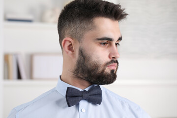 Portrait of handsome man in shirt and bow tie indoors
