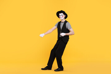 Funny mime artist in hat posing on orange background