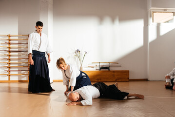 Martial Arts Instructor Supervises Ground Control Technique Practice in Dojo