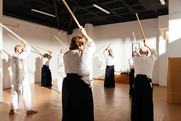 Martial Arts Students Practicing Wooden Sword Techniques in Dojo With Instructor