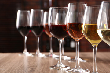 Different tasty wines in glasses on wooden table, space for text