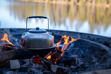 Camp kettle is heated on a bonfire. Hiking concept.