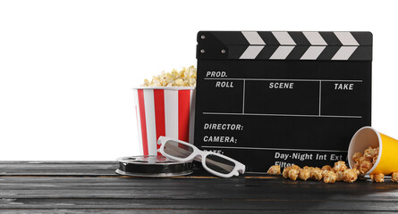 Movie clapper, buckets of tasty popcorn, glasses and film reel on wooden table against white...