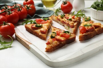 Tasty pizza toasts and ingredients on white marble table, closeup