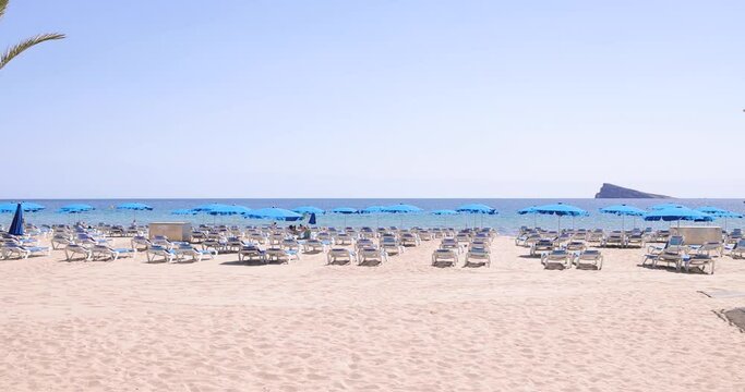 Footage of the beautiful city of Benidorm in Spain showing the busy Cala del Mal Pas or Levante Beach with people on the beach relaxing and sunbathing on vacation