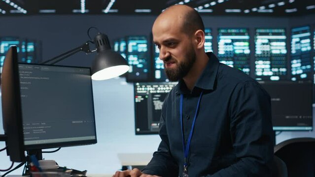 Hardworking engineer feeling happy and celebrating after being able to repair damages in data center facility. Cheerful man pleased after using PC to fix server cabinets errors
