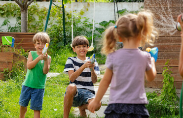 Smiling young children partake in water pistol play at backyard