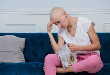 Woman coping with hair loss after chemo, sad hold wig in hands