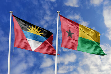  3d illustration. Antigua and Barbuda and Guinea-Bissau Flag waving in sky. High detailed waving flag. 3D render. Waving in sky. Flags fluttered in the cloudy sky.