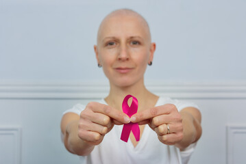Cancer fighter woman posing with support ribbon, focus on hands