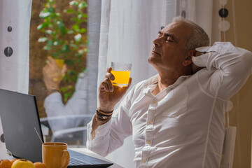 Fototapeta premium relaxed mature man having breakfast at his workplace