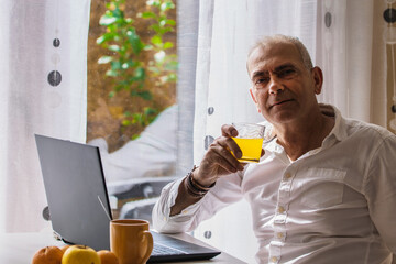 relaxed mature man having breakfast at his workplace