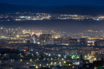 Fototapeta premium Top view of the night city. Ulan-Ude, Republic of Buryatia, Siberia, Russia. Beautiful night city landscape. Residential areas of a large Siberian city. Evening twilight.