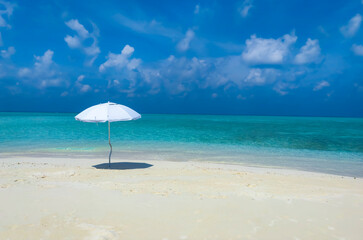 Summer tropical with white umbrella on the beach with  blue sky background