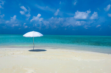 Fototapeta na wymiar Summer tropical with white umbrella on the beach with blue sky background