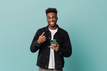 Cheerful sporty red-haired guy shows a finger on the smartphone screen on a blue background.