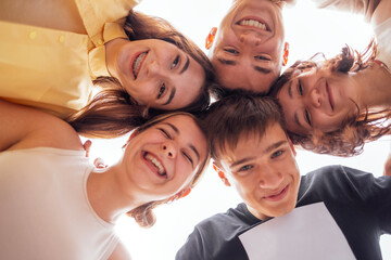 Funny smiling teenagers standing and looking down at camera. Group of cheerful friends in casual...