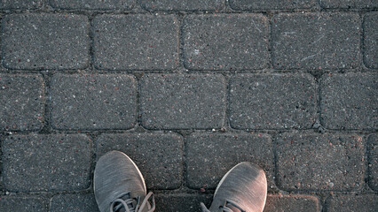 A person's feet are on a brick sidewalk - Powered by Adobe
