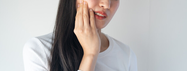 Teeth and gum problem concept. Asian young woman touching cheek and feeling toothache and pain face...