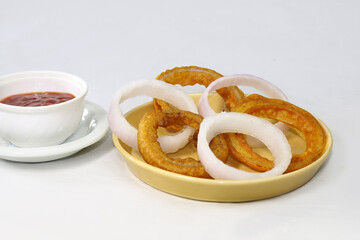 Homemade crunchy fried onion rings with tomato sauce and raw onion slices.