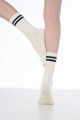 Cropped subject shot of female legs in white shadow-proof socks with two black stripes on the rim....