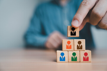 Businessman stacking human icon which print screen on wooden block cube for teamwork building by leadership and collaboration concept.