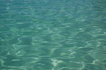 Blue water with ripples on the surface. Defocus blurred transparent blue clear calm water surface texture. Water waves with shining pattern texture background.