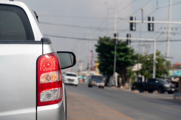 Pickup car silver color on the road stop and turn on brake light. Traffic light on the road. Blur...