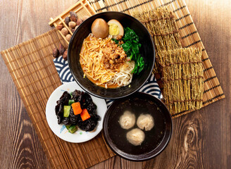 sesame paste noodles with Black Fungus, meatballs soup, minced pork meat, preserved egg and chopsticks served in plate isolated on napkin top view on table taiwan food