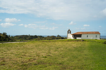 Iglesia con pequeño campanario en pradera junto al mar en Asturias