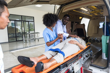 Black male doctor and black female nurse with injury patient lying on stretcher bed in ambulance