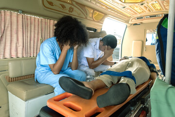 Black female nurse and male staff sitting in ambulance feeling sad with injury woman lying on...