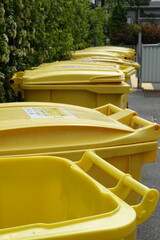 Poubelles jaunes de recyclage devant une copropriété