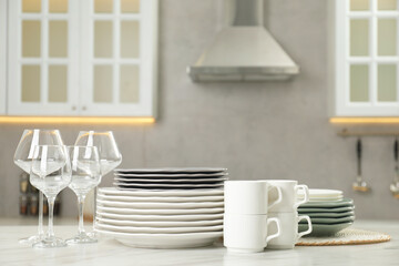 Clean plates, cups and glasses on white marble table in kitchen