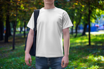 Mockup of a white men's T-shirt with a round neck, shirt on a guy with a backpack, front view, against the backdrop of a park, square.