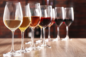 Different tasty wines in glasses on wooden table, space for text