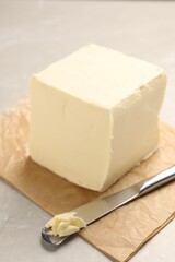 Block of tasty butter and knife on light table