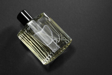Luxury men`s perfume in bottle on black background, above view. Space for text