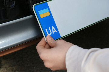 Woman installing vehicle registration plate outdoors, closeup