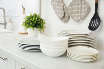 Clean plates and bowls on white marble countertop in kitchen